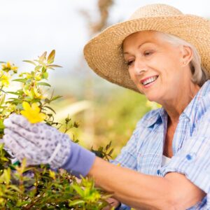 Older woman smiling while tending to her garden. 