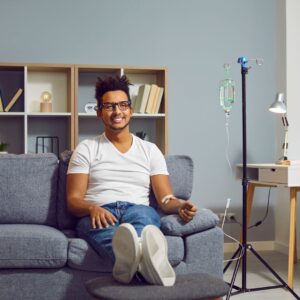 Man sitting in a chair getting IV therapy, smiling. 