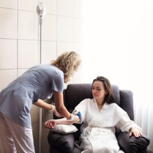 Woman sitting in a chair getting IV therapy administered by a professional. 