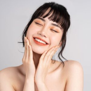 woman smiling while feeling skin