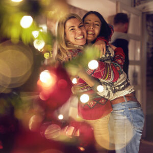 female friends hugging by a christmas tree