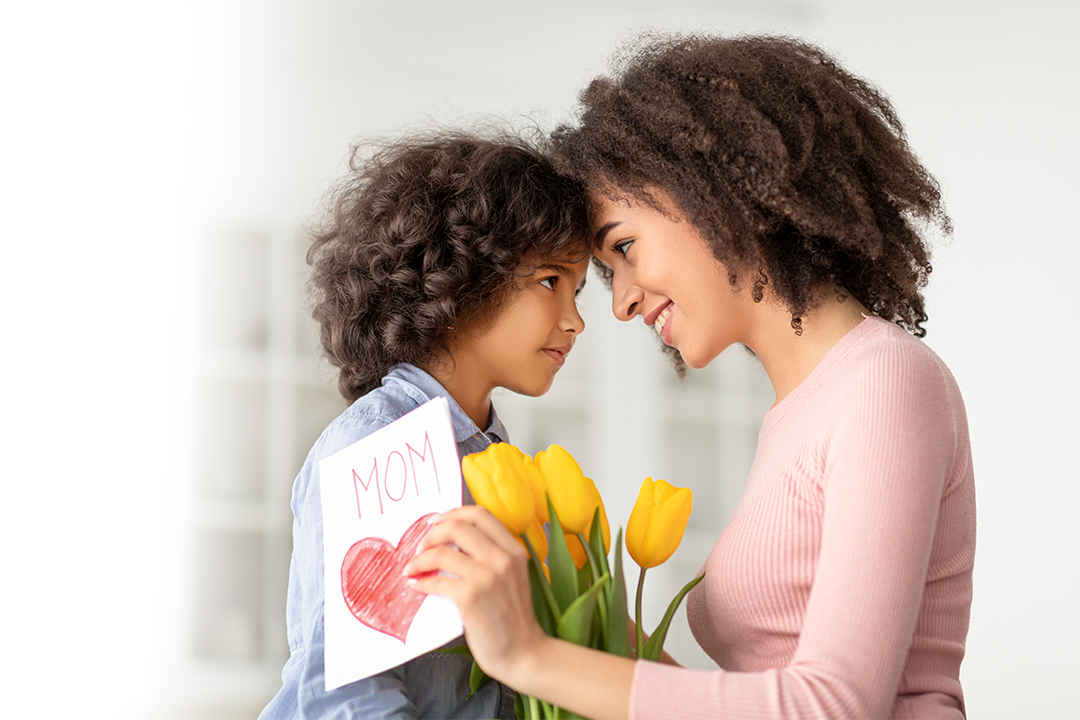 Happy Loving Family. Portrait of African American woman and little girl touching foreheads, looking at each other, daughter greeting mommy with mother's day, lady holding card and bunch of flowers